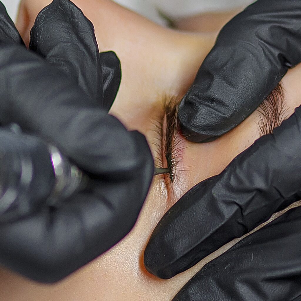 Permanent make up eyeliner procedure, applying on young girl. Close-up. Young beautiful woman making permanent makeup in cosmetology salon. Young girl applying permanent eyeliner in beauty studio